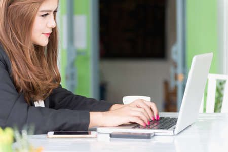Asia young business woman sitting in a cafe with laptop and coffee, business conceptの写真素材