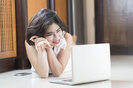 happy asia woman lying on floor with the laptop at homeの写真素材