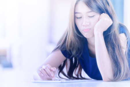 asia girl lying on floor and looking into tablet computer at homeの写真素材