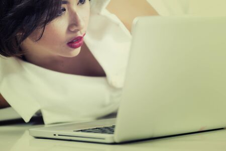 Asia office woman lying on floor with open laptop at homeの写真素材