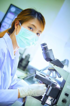scientist looking through a microscope in a laboratory hospitalの写真素材