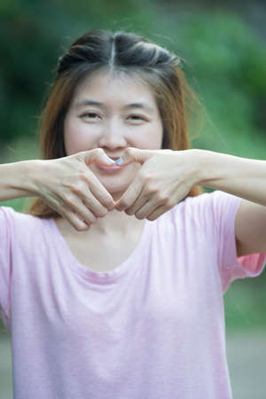 asia smiling cheerful young woman making heart sign with hands, Positive human emotion expression feeling life perception attitude body language, happy conceptの写真素材