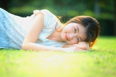 asia beautiful young woman lying on green grass in holidayの写真素材