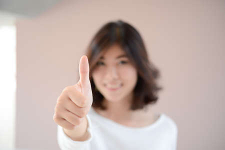 asia happy smiling  woman with thumbs up gesture, blur backgroundの写真素材