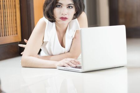 Asia office woman lying on floor with open laptop at homeの写真素材