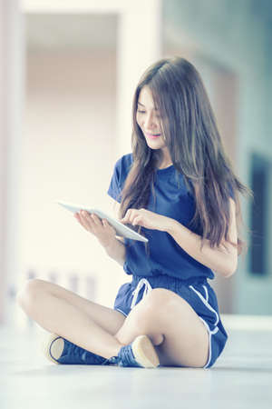 Asia beautiful young girl with tablet on floor indoor