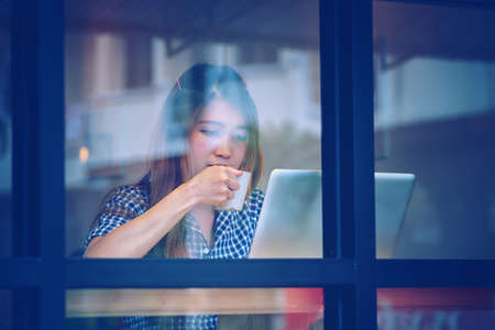 asia young woman drink coffee and working on laptop in cafe, Vacations concept.の写真素材