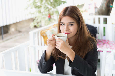Asia young business woman sitting and drinking hot coffee in cafe, business conceptの写真素材