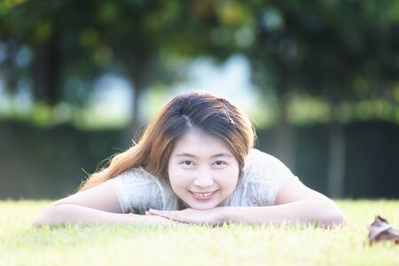 asia beautiful young woman lying on green grass in holidayの写真素材