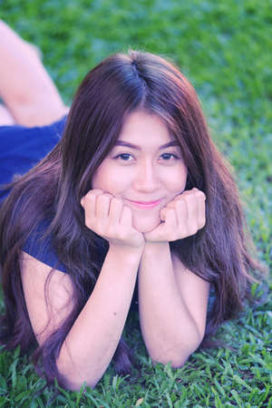 asia beautiful smiling woman lying on grass outdoor. She is absolutely happy.