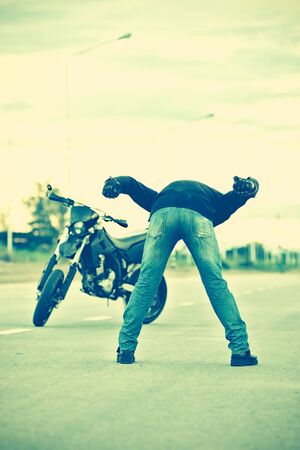 Biker standing relax after driving motorbike far a way on sunset, vintage effectの写真素材