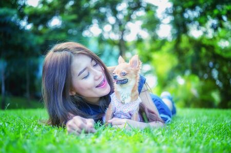 portrait of asia young  woman with her beautiful dog lying on grassの写真素材