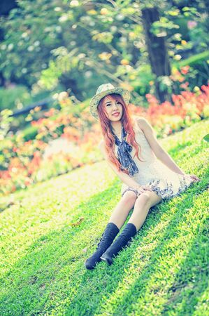 fashion shoot of asia young women sitting on grass in garden, vintage effectの写真素材