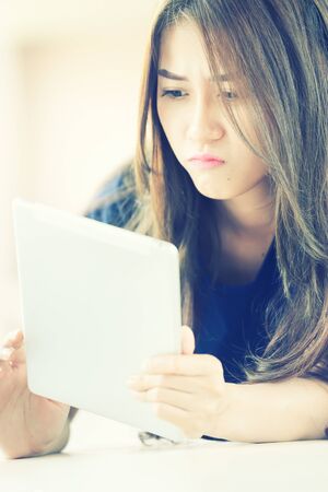 asia girl lying on floor and looking into tablet computer at home