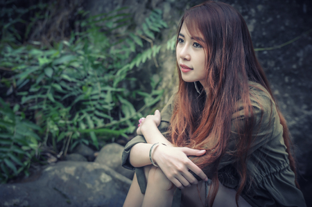 Asia Beautiful young girl sitting on the stone in water fallの写真素材