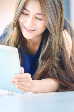 asia girl lying on floor and looking into tablet computer at homeの写真素材