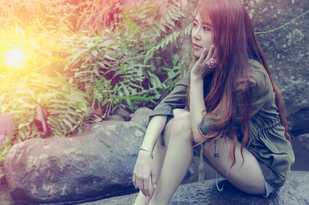 Asia Beautiful young girl sitting on the stone in water fallの写真素材