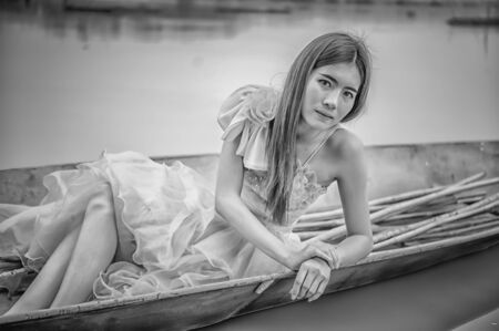 Portrait of Asia Beautiful woman in yellow dress sitting on boat, black and white imageの写真素材