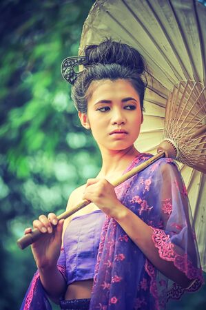 ancient Thai Woman In Traditional dress Of Thailand with vintage umbrella, vintage effectの写真素材