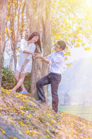 portrait of asia happy couple standing in the autumn park under treeの写真素材