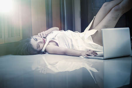 Asia woman using smart phone and laptop lying on the floor at home, add flare, vintage styleの写真素材