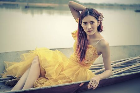 Portrait of Asia Beautiful woman in yellow dress sitting on boatの写真素材
