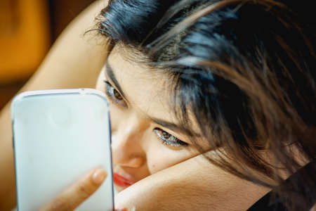 Asia woman lying on the floor with a mobile phone in the roomの写真素材