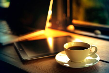 Laptop, tablet, smartphone and a white cup of coffee on wooden background.の写真素材