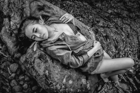 Asia beautiful young sexy girl lying down on a rock in water fall, black and white imageの写真素材