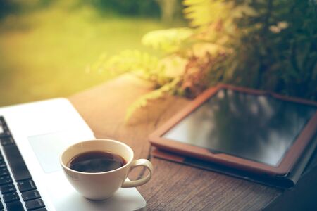 Laptop, tablet, smartphone and a white cup of coffee on wooden background.の写真素材