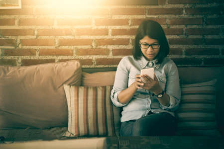 Asian woman on the couch using phone at home in the living room