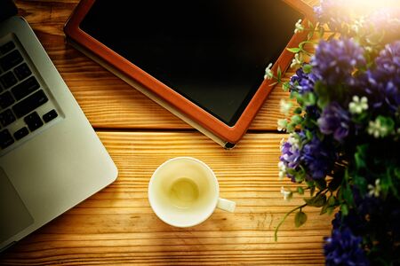 Laptop tablet and empty white coffee cup on wooden table, in cafe