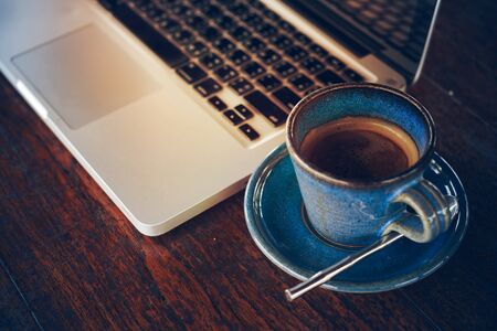 hot coffee cup and laptop on wood table, in morningの写真素材