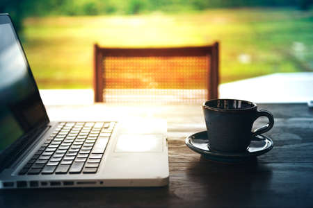 hot coffee cup and laptop on wood table, in morningの写真素材
