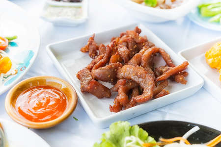 Sun dried pork fried on white dish with chilli sauce in restaurantの写真素材