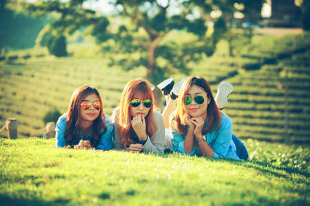 three asia smile girl lying on grass at chuifong tea farm in spending free time, relaxingの写真素材
