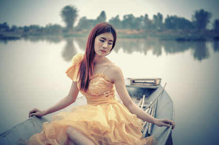 Portrait of Asia Beautiful woman in yellow dress sitting on boatの写真素材