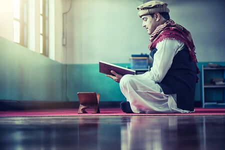 Religious muslim man reading holy koran inside the mosqueの写真素材