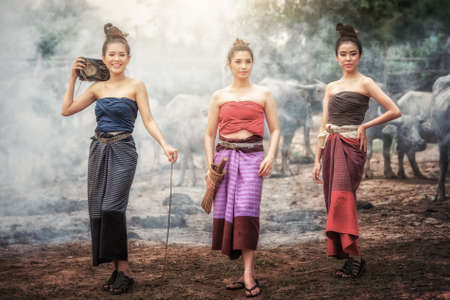 three Beautiful Asian women dressed in national costume with buffalo at farmland., thai styleの写真素材