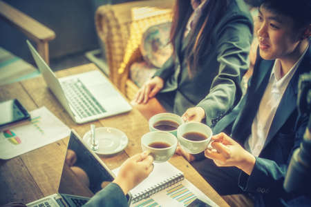 young Business people clink hot coffee to successの写真素材