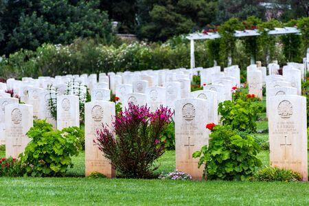 Sun shining on gravestones with flowers on a beautiful and well cared War Cemetery in Greeceのeditorial素材