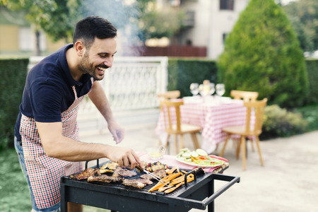 Handsome man preparing barbeque in the yardの写真素材