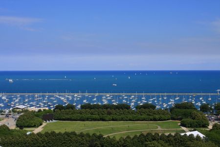 Park with trees next to harbor with sailboatsの写真素材