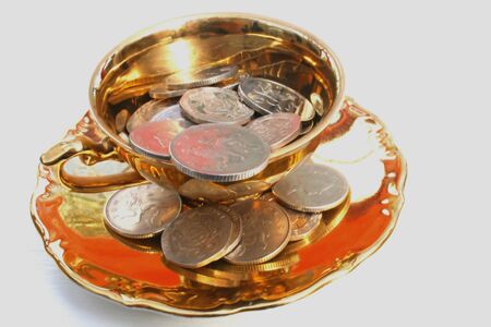 silver coins and gold coloured tea cup.の写真素材