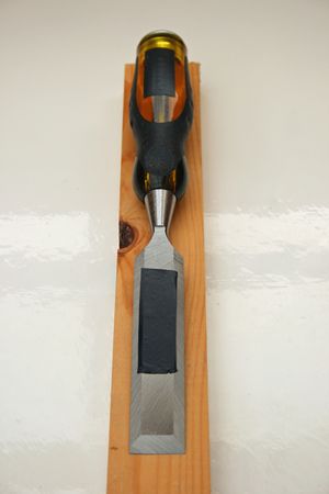 A woodworking chisel on a length of wood.