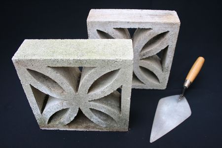 Breeze blocks and bricklaying trowel on black background.