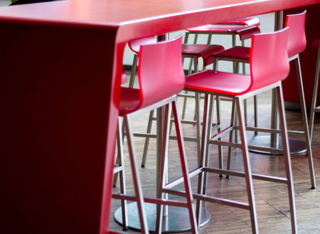 Red, tall bar chairs in a row with one of them pulled back の写真素材