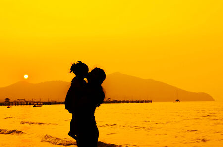 silhouettes of mother and baby kissing on sunsetの写真素材