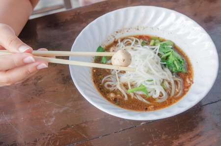 Hand holding chopstick take meatball, hot and spicy noodleの写真素材