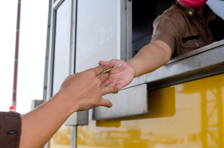 Man paying money at toll booth in thailand